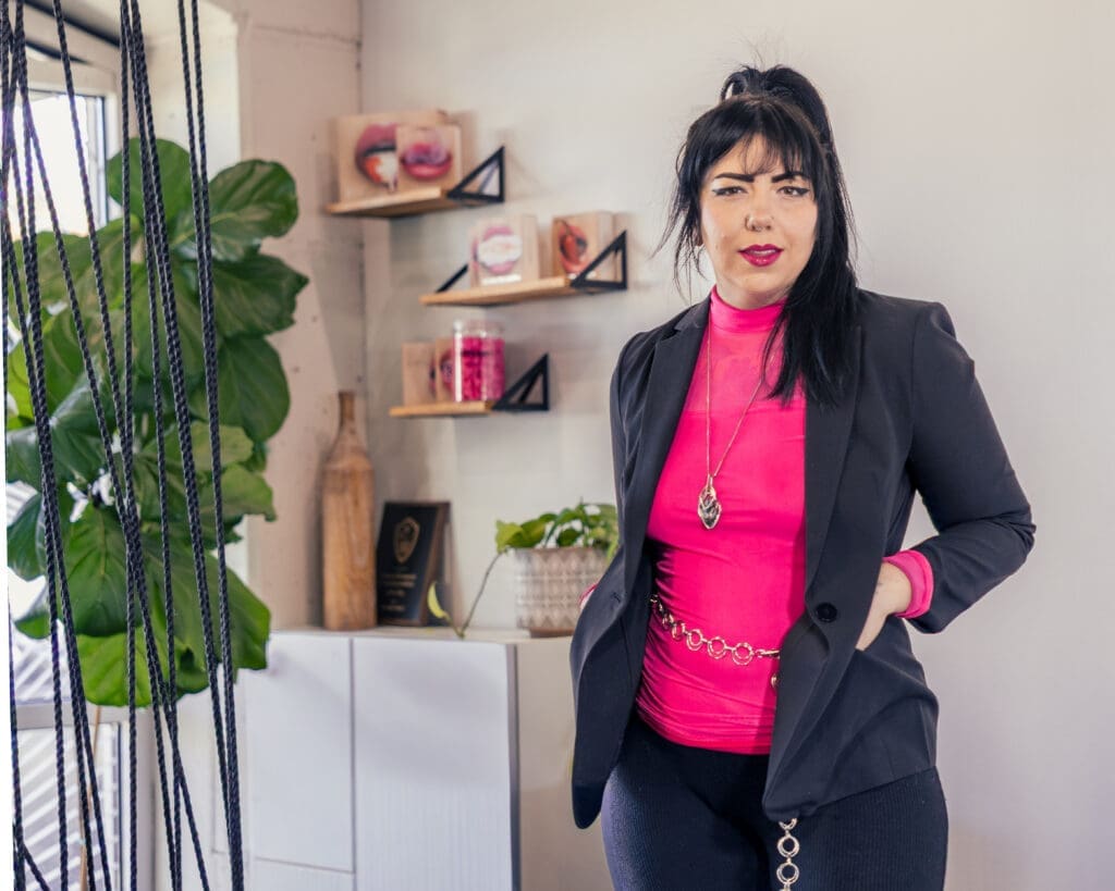 Salt Lake City permanent makeup artist portrait with black blazer, pink top, and modern studio aesthetic